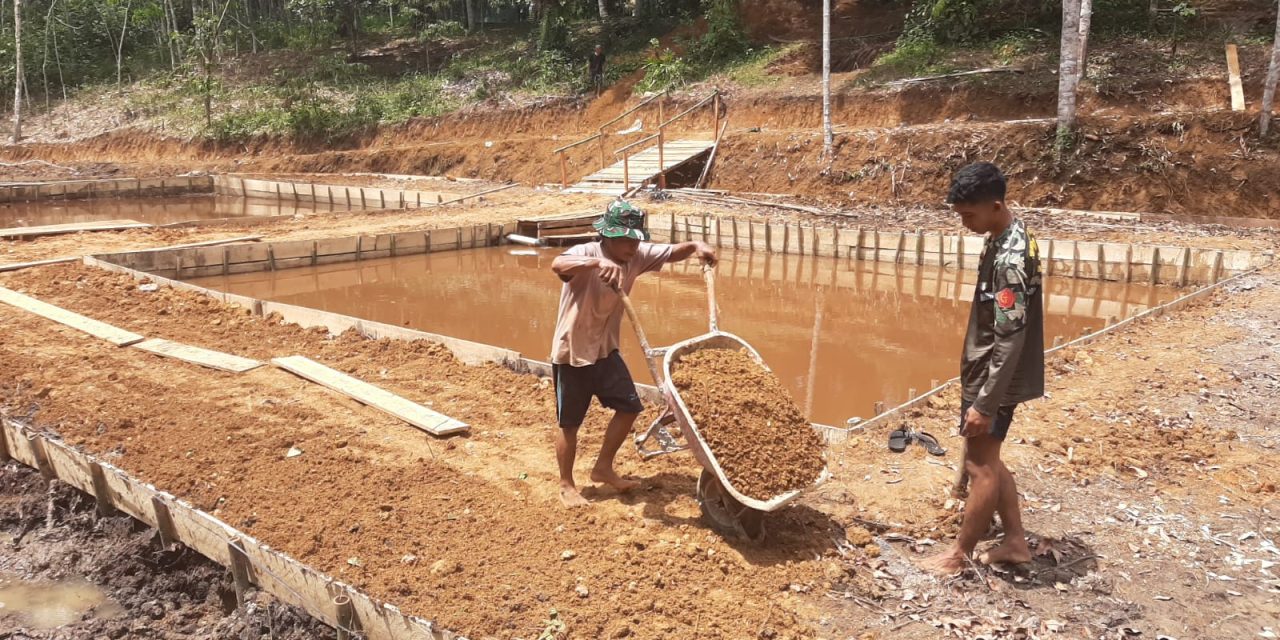 Anggota Satgas TMMD dan Warga Perkeras Bantaran Kolam Ikan